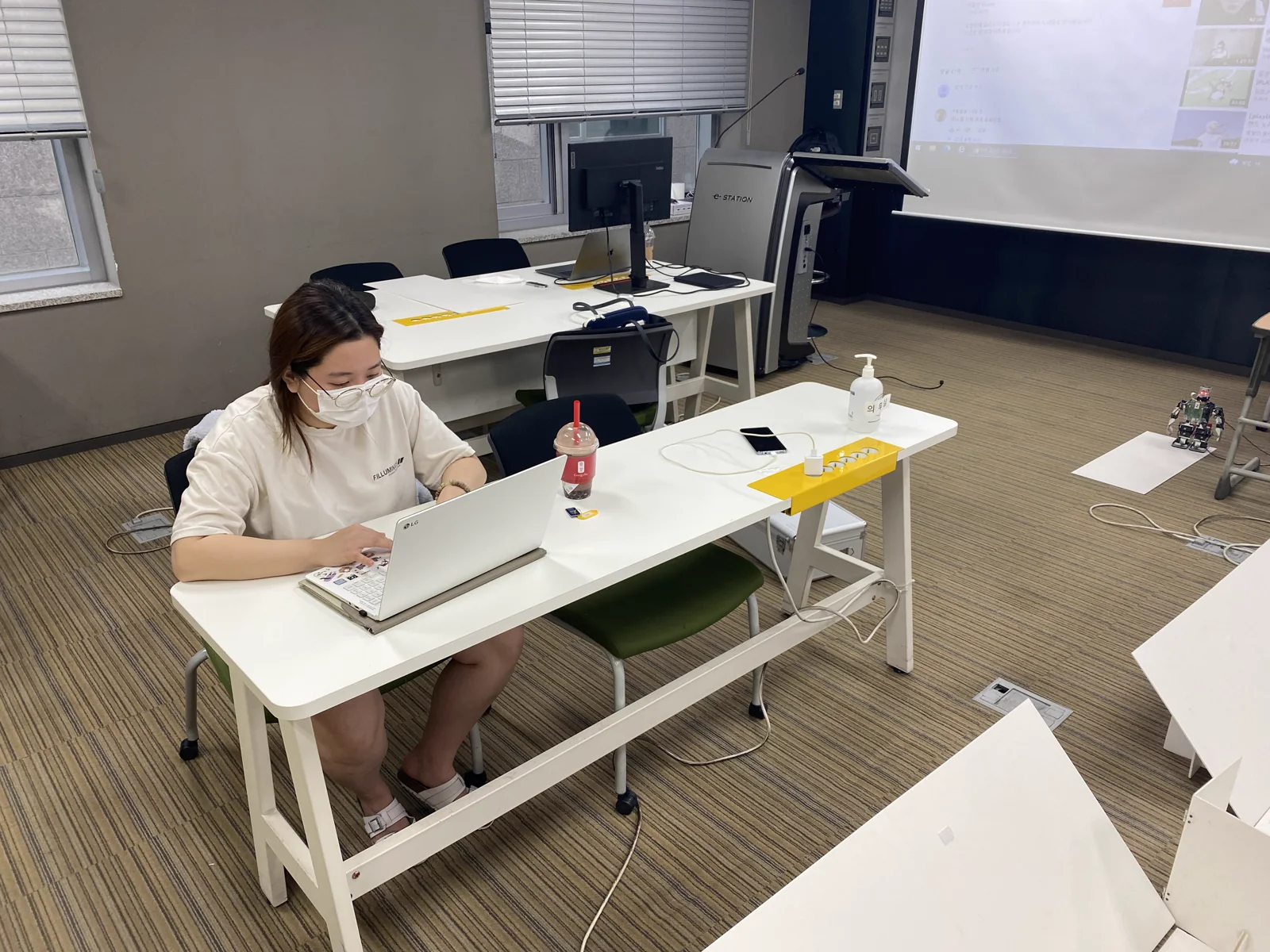 로봇 미션 코스 옆 책상에서 노트북을 보며 작업하는 팀원